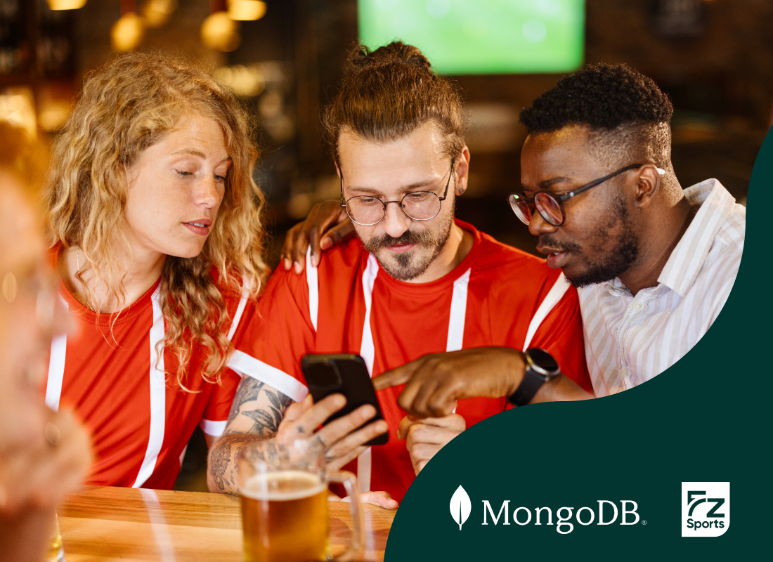 Group of three people gathered around a table, using a cell phone.